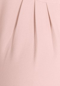 Light pink fabric featuring a textured finish with subtle pleating details, creating depth and dimension in the material.