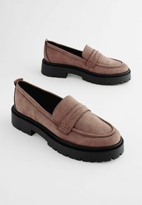 Mocassini in suede di colore malva con punta arrotondata, dettaglio cucito e una suola chunky in gomma nera. Design minimalista senza hardware visibile.