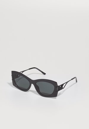 Ochelari de soare negri cu formă angulară, supradimensionată în stil cat-eye. Au lentile întunecate și accente din metal pe brate. Fabricate din plastic mat.