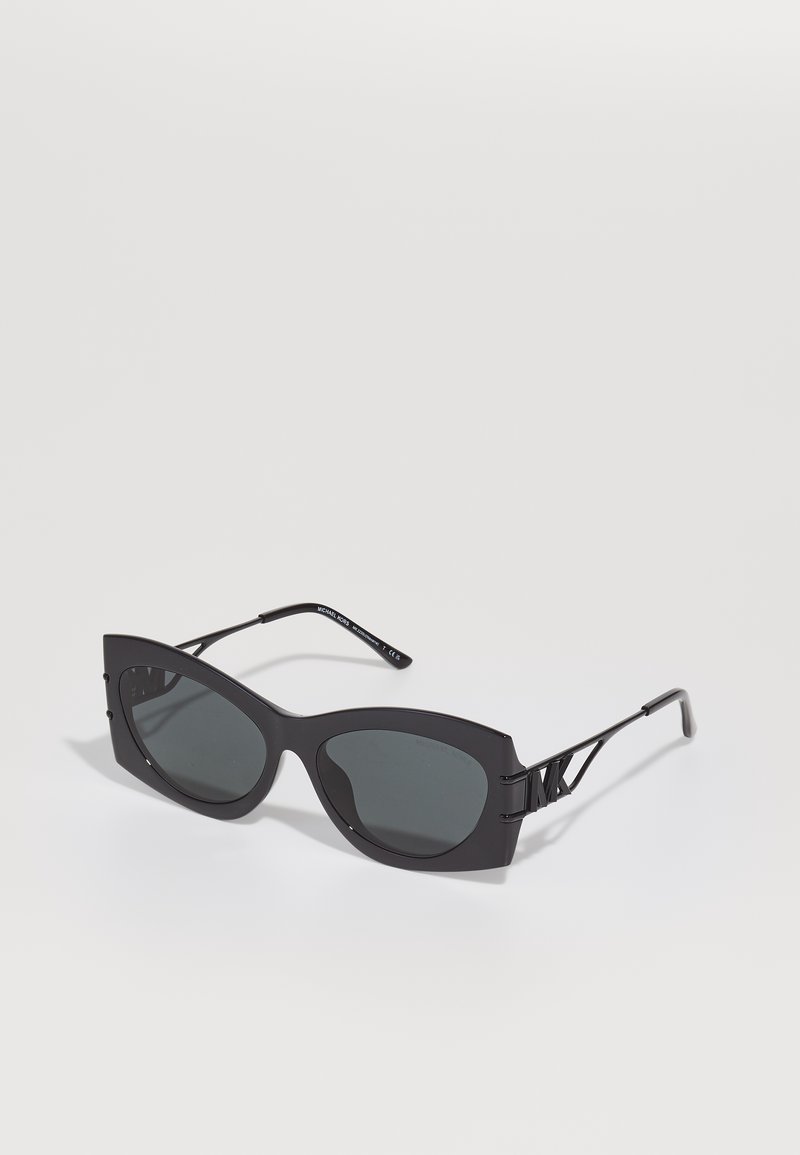 Ochelari de soare negri cu formă angulară, supradimensionată în stil cat-eye. Au lentile întunecate și accente din metal pe brate. Fabricate din plastic mat.