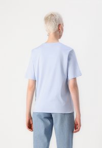 Short-sleeve, light blue t-shirt in soft cotton, featuring a round neck and a relaxed fit, paired with high-waisted light denim jeans.