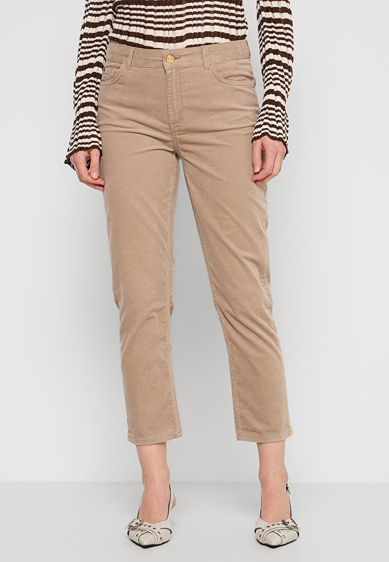 Beige Cordhose mit schlanker Passform, vorn mit Knopfverschluss, fünf Taschen und leicht verkürzter Länge. Kombiniert mit einem gestreiften Oberteil.