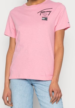 Camiseta de algodón rosa con mangas cortas, cuello redondo, con un logo negro y nombres de ciudades impresos en la parte delantera, corte relajado.