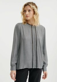 Zwart-witte geruite blouse met lange mouwen, een hoge halslijn, geplooide details en manchetwrists. Glad stof met een lichte glans.