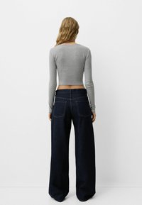 Gray long-sleeve cropped top paired with wide-leg dark denim jeans, featuring a clean design and back pockets.