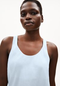 Light blue sleeveless top with a scoop neckline, made of smooth fabric. Simple design with no visible patterns or embellishments.