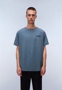 Lyseblå crewneck T-shirt i blødt bomuldsstof med lille mørk logo på brystet. Afslappet pasform med korte ærmer.