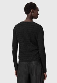 Zwarte gestructureerde lange mouwen top met een geribbelde patroon, ronde halslijn en nauwsluitende silhoutte, gecombineerd met zwarte leren broek.