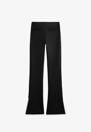 Mustat levenevät housut, joissa on sileä pinta, kahdella takataskulla ja valkoisilla yksityiskohdilla helmoissa. Minimalistinen muotoilu ja istuva leikkaus.