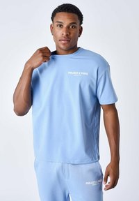 Lichtblauwe t-shirt met korte mouwen en een ronde halslijn, met 'PROJECT X PARIS' in het wit gedrukt op de linkerborst. Gladde stofstructuur.