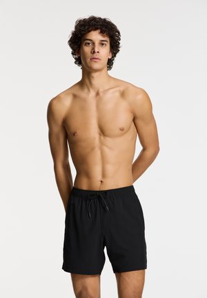 Black swim shorts with an elastic waistband and adjustable drawstring. Smooth texture and knee-length design, minimal detailing.