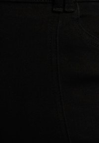 Jeans di denim neri con una texture liscia, caratterizzati da un classico design a cinque tasche e cuciture visibili lungo le cuciture.