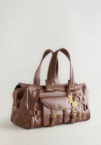 Sac à main en cuir marron avec deux poignées, poches latérales zippées, rabat avant, finitions en métal doré et un pendentif décoratif.