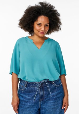 Teal korte mouwen blouse met een V-hals, gemaakt van een lichtgewicht stof, gecombineerd met hoge taille blauwe spijkerbroek met strik.