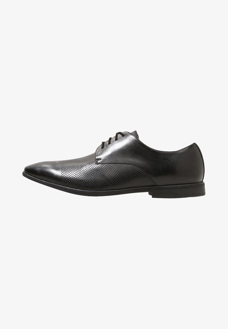 Chaussure habillée pour homme en cuir noir poli avec des détails perforés, fermeture à lacets et bout pointu sur fond blanc.