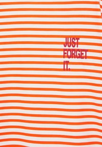 Tissu à rayures horizontales blanches et orange avec le texte « JUST FORGET IT. » imprimé en rouge sur le côté droit.