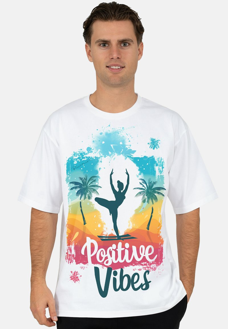 Wit T-shirt met een kleurrijk ontwerp van een danseressilhouet, palmbomen en de tekst "Positive Vibes" in roze en turkoois.