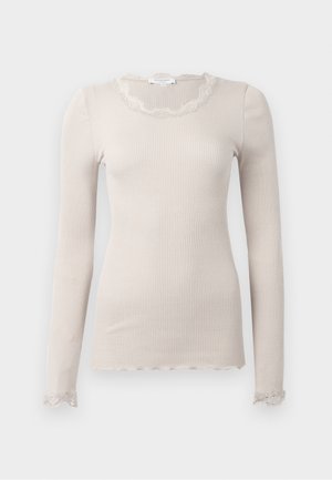 Beige langærmet top lavet af ribbet stof, har en scallop-lace halsudskæring og kant, med delikate lace-detaljer ved ærmerne.