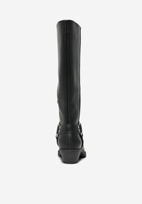 Botte noire en cuir haute jusqu'au genou, avec une finition lisse, un petit talon et une sangle décorative agrémentée d'ancres en métal à la cheville.