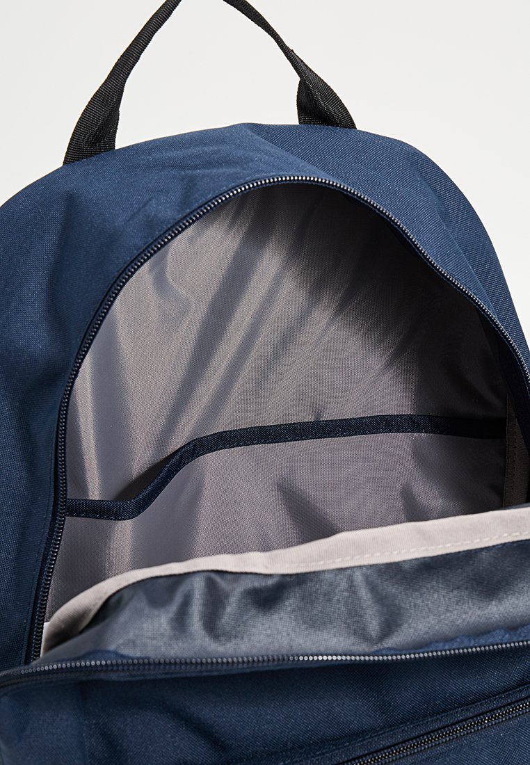 Sac à dos bleu marine avec une fermeture zippée, doté d'un intérieur spacieux, d'une doublure lisse et d'une section divisée pour une meilleure organisation.