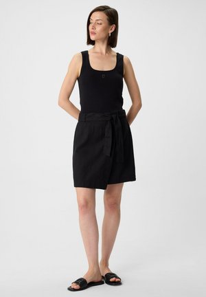 Black sleeveless top, black wrap skirt with a tie belt, and black slide sandals, featuring smooth textures and a simple, minimalist design.