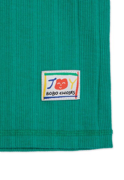 Tyrkysový ribovaný textil s farebnou tkanou nášivkou s nápisom "JOY BOBO CHOSES," hravými písmenami a dizajnom usmievajúcej sa tváre.