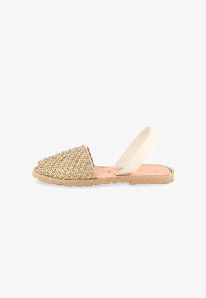 Beige vævet lukket tå flad sandal med lys tan sål og hvid elastisk ankelstrop.