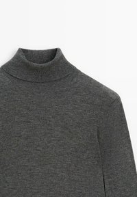 Maglione a collo alto in maglia costina di colore grigio scuro con maniche lunghe, disteso su una superficie bianca.