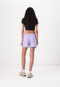 Shorts en coton lilas avec une taille élastique, associés à un top noir court. Ourlet soigné et coupe décontractée, conçus pour le confort.