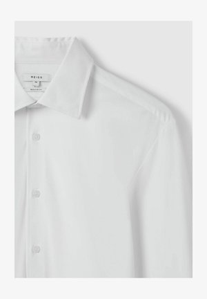 Chemise blanche à boutons, coupe régulière, fabriquée en tissu lisse. Présente un col structuré et un subtil éclat, avec une simple patte de boutonnage.