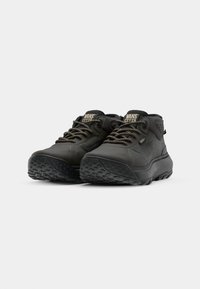 Svart høyhælte sneakers med en glatt gummioverdel, teksturert såle, forsterkede snørehull og kraftige snører med en subtil logoakcent.