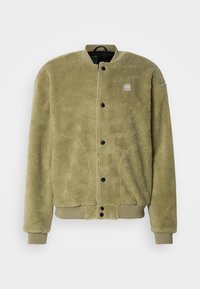 Veste bomber en polaire vert olive avec fermeture à boutons-pression, poignets et ourlet côtelés, et petite étiquette logo rectangulaire sur la poitrine.