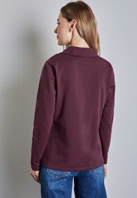 Mauve langemouwen shirt met een kraag, gladde textuur en een ontspannen pasvorm. Gepaard met denim jeans, gezien vanuit de achterkant.