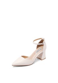 Chaussure à talon haut blanche à bout fermé avec bride à la cheville et boucle, talon bloc, et matériau en cuir lisse sur fond blanc.