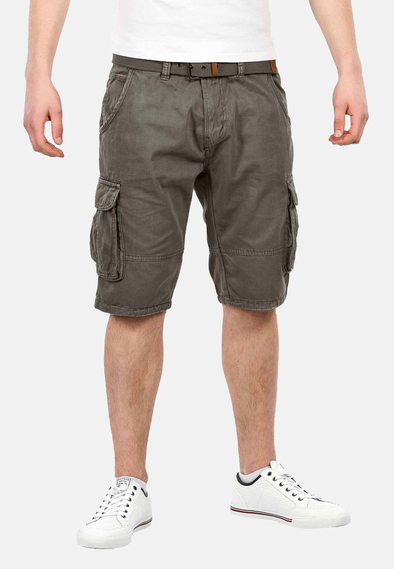 Cargo-Shorts aus olivgrünem Baumwollmischgewebe, knielang mit Seitentaschen, genähten Details und einem braunen Gürtel. Kombiniert mit weißen Sneakern.
