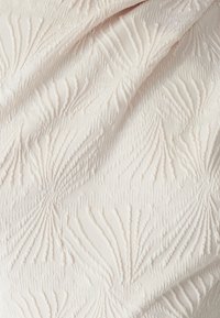 Tekstūrēta auduma ar paceltu, lapu līdzīgu rakstu maigos off-white toņos, izceļot smalku dizainu ar dimensiju detalizāciju.