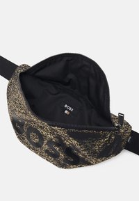 Zwart met goud patroon heuptasje, met een ritssluiting en het "BOSS"-logo. Binnenkant is van zwart stof met een klein merkvlaggetje.