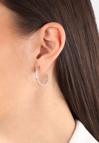 Pendientes de aro de plata con un diseño delgado y abierto que presenta pequeños y coloridos gemas a lo largo del borde. Acabado suave, ligero.