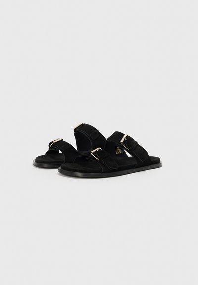 Sandali neri in suede con doppie cinghie regolabili e fibbie metalliche; suola piatta e design semplice e aperto per ventilazione e comfort.