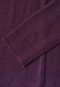 Strickkleid in tiefem Lila mit einem strukturierten Muster. Der Ärmel zeigt eine kontrastierende glatte Strickart. Insgesamt ein reichhaltiger und abwechslungsreicher Stoff.