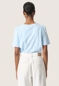 Lys blå bomulds t-shirt med pufærmer og rund halsudskæring. Kombineret med strukturerede hvide bukser med et synligt bagetiket.