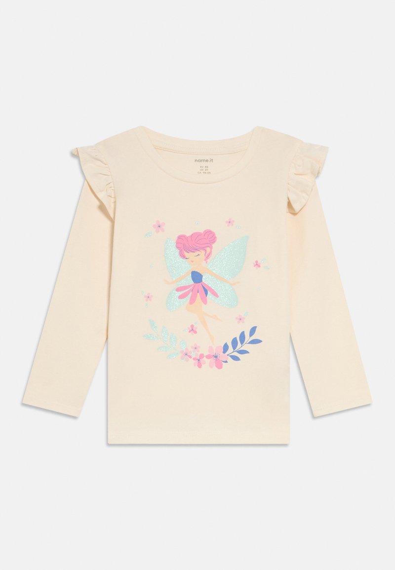 Langärmliges beige Baumwollhemd mit Rüschen, verziert mit einem glitzernden Feenmotiv, umgeben von Blumen und Blättern.