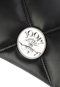 Črna usnjena torbica z quiltirano teksturo, opremljena s srebrnim okroglim logotipom z napisom "JOOP! JEANS" in dekorativnim šivanjem.