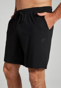 Schwarze Schwimmshorts aus leichtem Material, mit elastischem Bund, Kordelzug und seitlichen Taschen. Dezentes Logo-Detail am Bein.