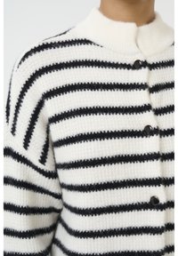 Cardigan a righe bianche e nere, texture lavorata a maglia, colletto rotondo, chiusura con bottoni frontali, con bottoni scuri su un tessuto morbido e accogliente.