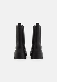 Black leather ankle boots with a chunky sole, featuring a seamless design, pull tabs, and a smooth finish.