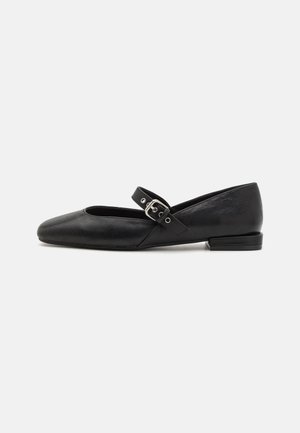 Chaussure plate Mary Jane noire avec bout arrondi et bride à boucle argentée, vue de côté sur un fond clair uni.