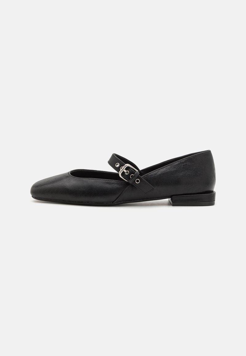 Chaussure plate Mary Jane noire avec bout arrondi et bride à boucle argentée, vue de côté sur un fond clair uni.