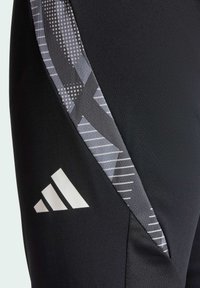 Schwarze Sporthosen mit einem strukturierten Seitenpanel, das ein geometrisches graues Muster aufweist, sowie einem weißen Adidas-Logo am unteren Bein.