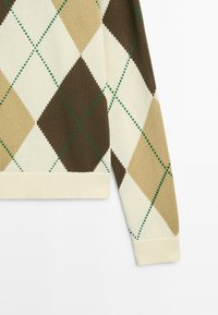 Pull en maille à manches longues avec motif losanges beige, marron et crème, avec des lignes vertes cousues sur fond blanc.